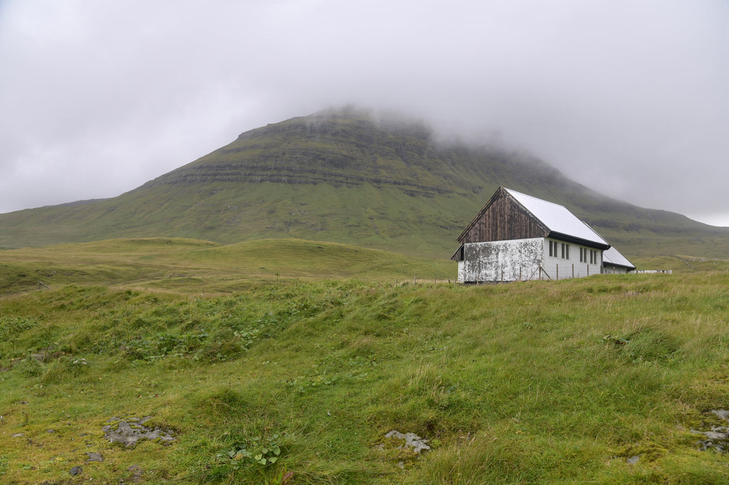 A little white shack along the foggy cliffs of the Faroe Islands. Fine Art Photography. Kristen Olivares.