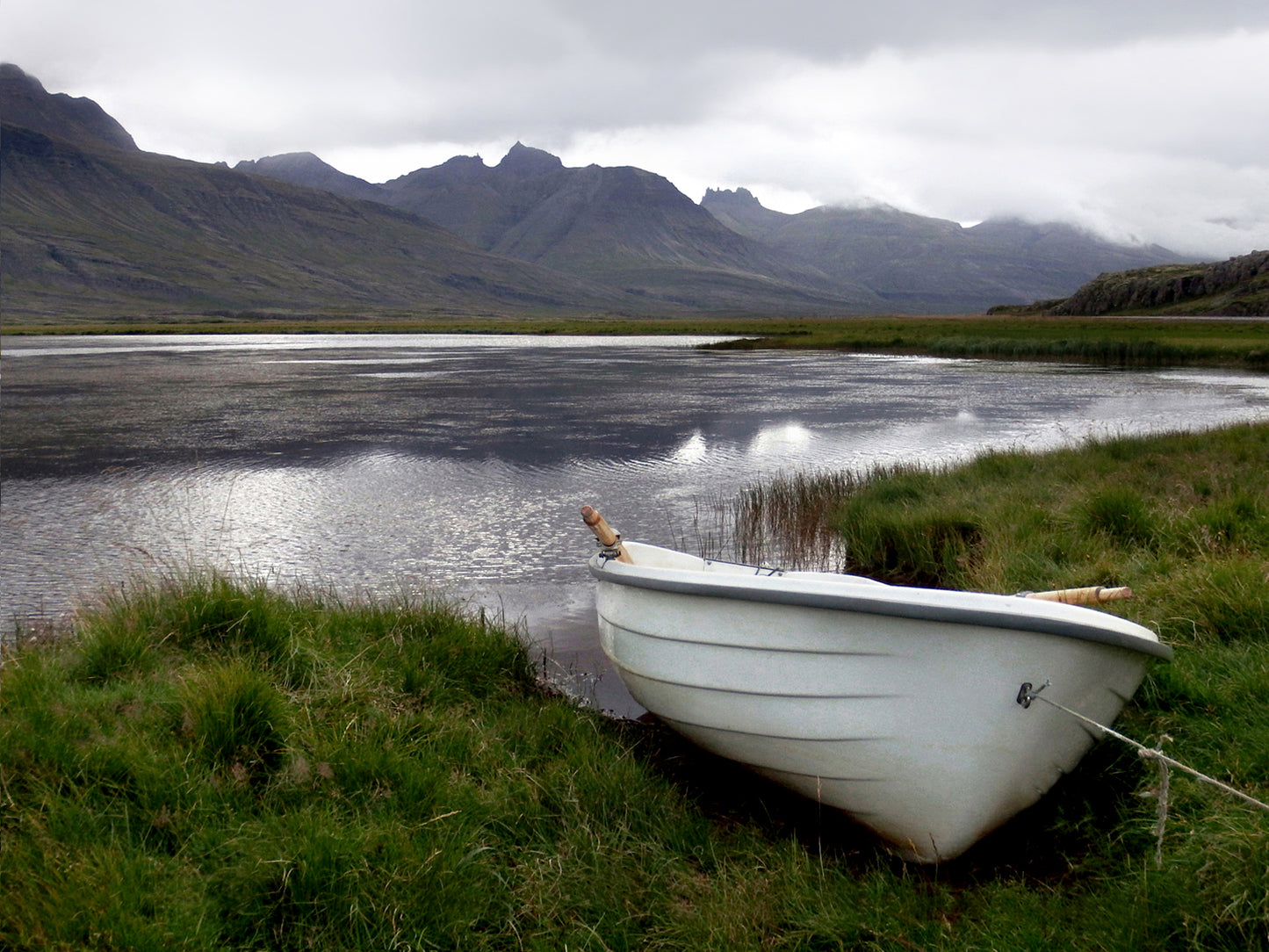 A beautiful little white row boat pulled up upon the desolate shore of Iceland. Canvas wall art. Fine art photography by Kristen Olivares.