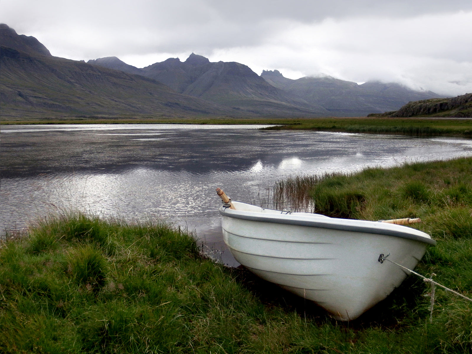 A beautiful little white row boat pulled up upon the desolate shore of Iceland. Canvas wall art. Fine art photography by Kristen Olivares.