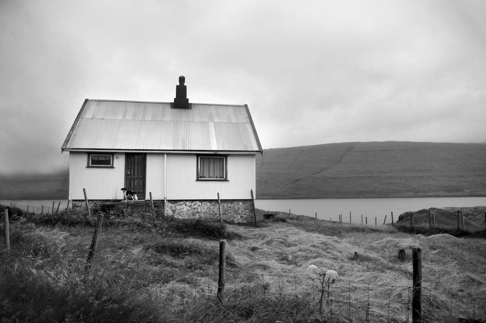 Black and white image of an old house tucked away in the Faroe Islands. Framed fine art photography by Kristen Olivares